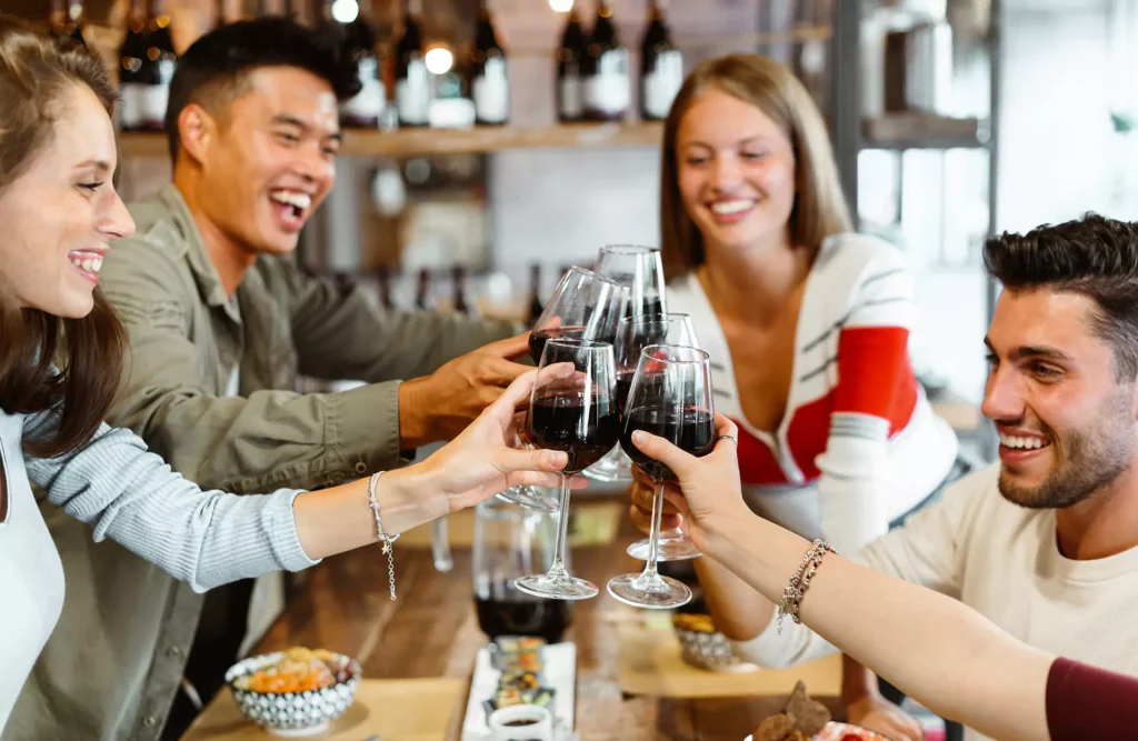 People around a table cheering with wine glasses